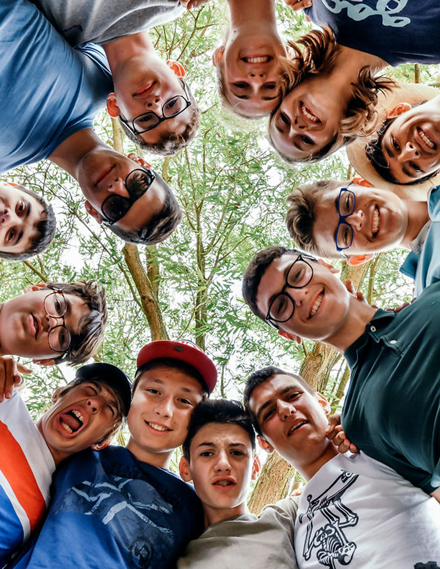 A group of homestay students in a circle looking down and smiling
